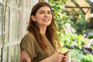 Attractive woman in a smartphone in a greenhouse for plants.