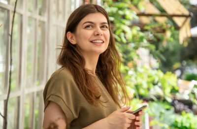 Attractive woman in a smartphone in a greenhouse for plants.