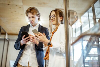 Business man and woman with smartphones in the office