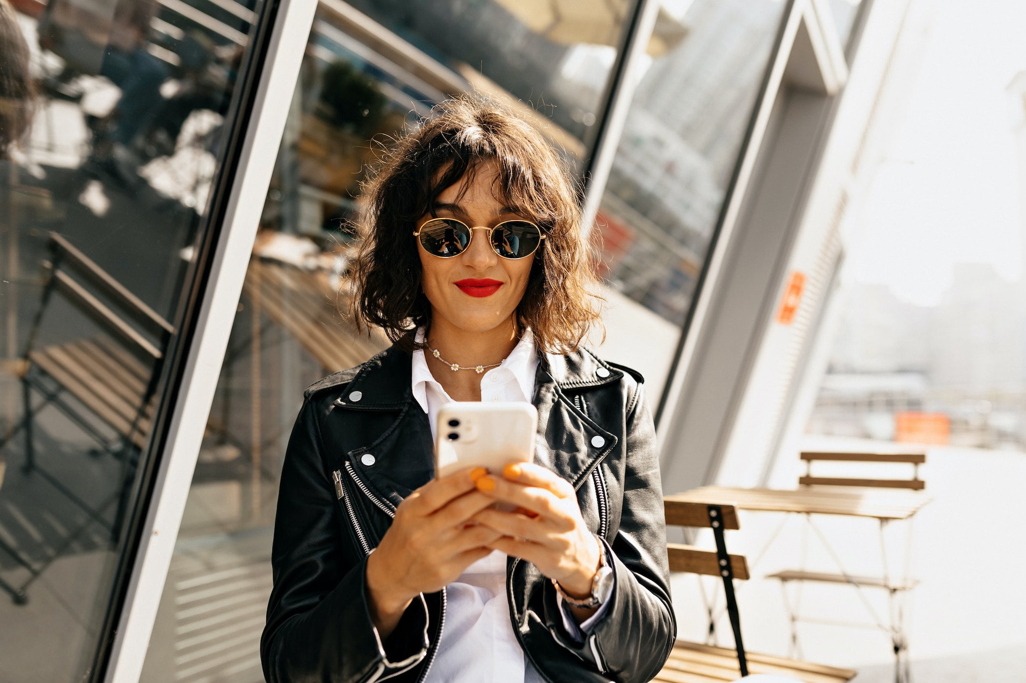 Modern stylish woman with short hairstyle wearing sunglasses using smartphone