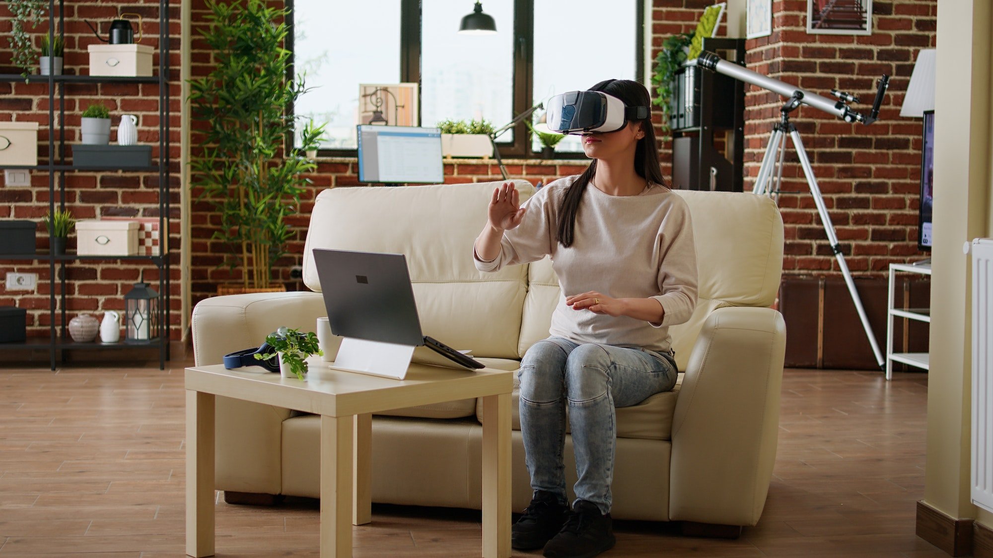 Playful woman with VR goggles playing on metaverse inside living room