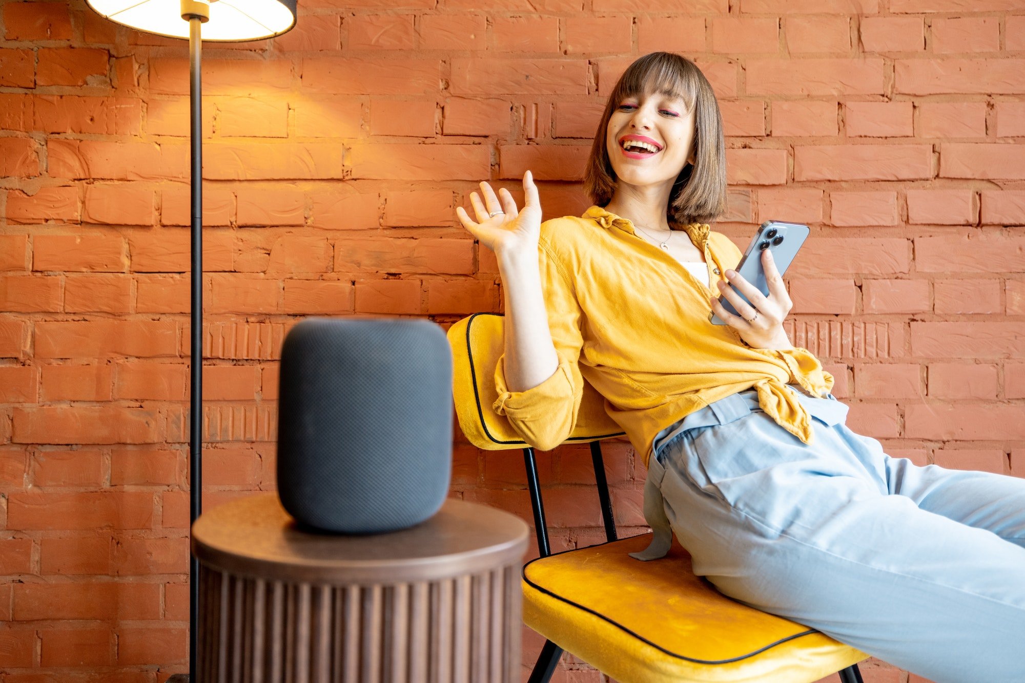 Woman with smart speaker and phone at home