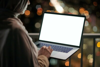 Young contemporary businesswoman with laptop standing on balcony