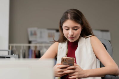 Young fashion designer woman check smartphone call to customer at office