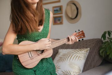 Close up photo of woman playing ukulele at home, happy people making music