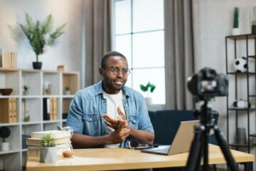 Positive guy recording video blog on camera at home