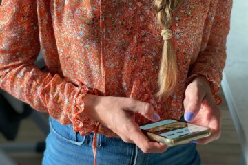 A stylish millennial woman with a long braid is using her mobile device to check her social media