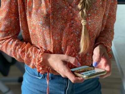 A stylish millennial woman with a long braid is using her mobile device to check her social media