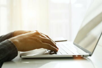 Close up of man hands using laptop at home office. Concept of searching web, browsing information