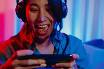 asia girl gamer wear headphone competition video game online with smartphone.