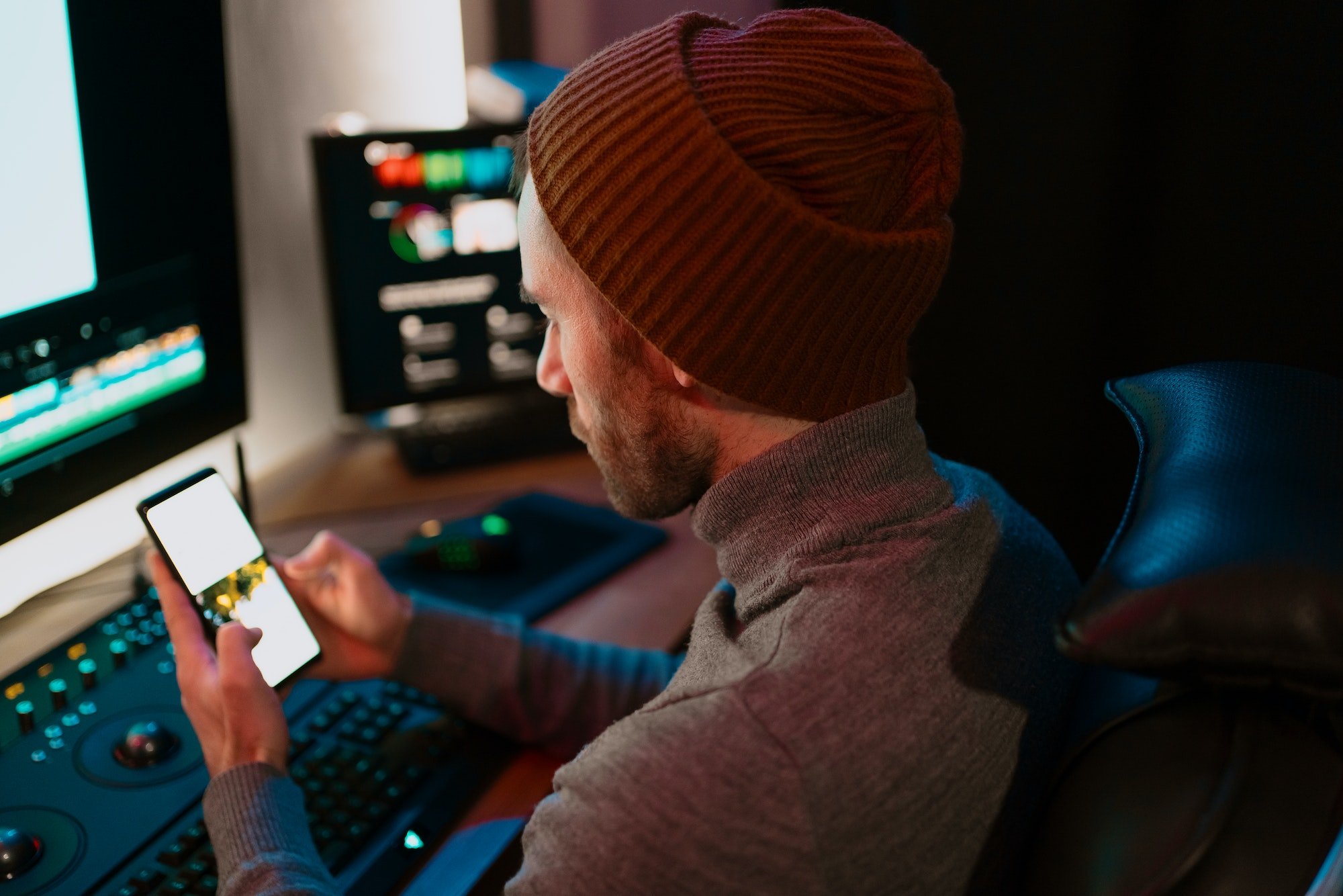 Male Video Editor sitting at his Computer using phone blank screen