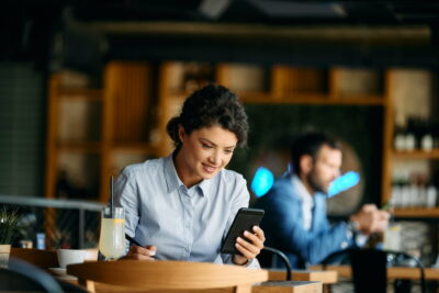 Young businesswoman reading text message on smart phone in a cafe.