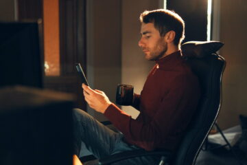 Young man working at home using a smartphone and computer.