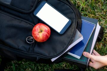 Back to school. Backpack, books, apple, smartphone with white screen mock up friendly