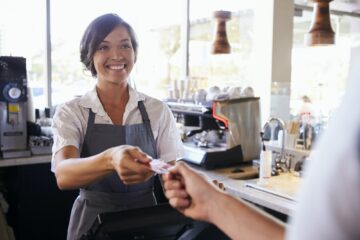 Cashier Accepts Card Payment From Customer In Delicatessen