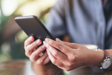 Closeup image of a woman holding , using and looking at smart phone