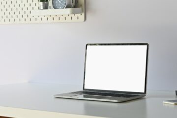 Mockup laptop computer on working table with empty screen display.