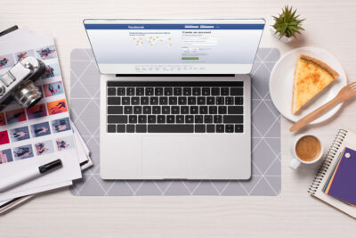 office desk with laptop with facebook website on screen, flat lay